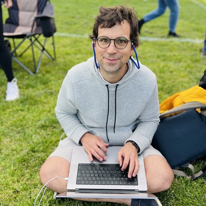 Img: grass, person, sitting, laptop, pc, adult, male, man, glasses, jeans