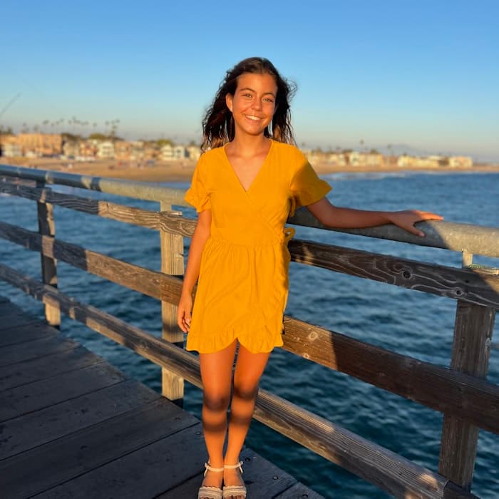 Img: waterfront, dress, pier, handrail, person, boardwalk, sandal, beachwear, smile, sleeve